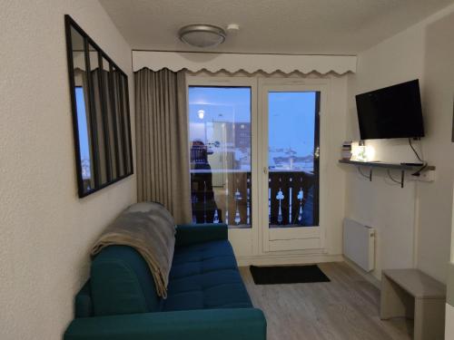 a living room with a blue couch and a window at CHALET CLUB VAL CLARET 1 46 in Tignes