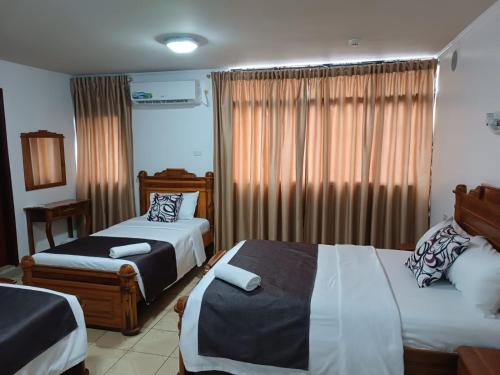 um quarto de hotel com duas camas e uma janela em Hostal Bicentenario em Guayaquil