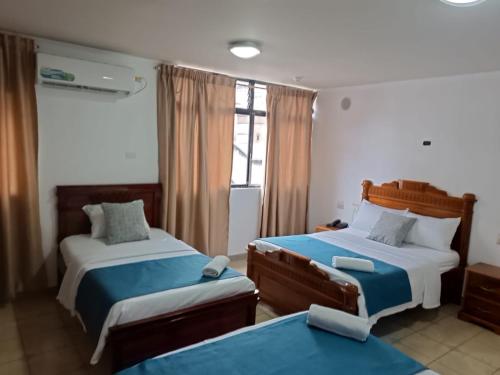 a bedroom with two beds and a window at Hostal Bicentenario in Guayaquil