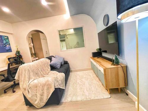 een woonkamer met een bank en een televisie bij Cozy little home C216 near Central Festival in Chiang Mai