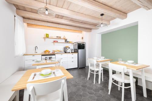 a kitchen with white cabinets and wooden tables and chairs at B&B Le Zucche in Belluno