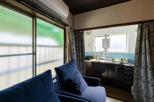 a living room with a couch and a kitchen with a window at Bed&Cafe Onzo オンゾー in Onomichi