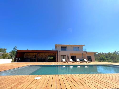 une maison avec une piscine sur une terrasse en bois dans l'établissement Casa Sandro, à Sainte-Lucie de Porto-Vecchio