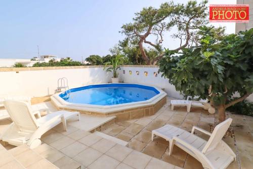 un patio con bañera de hidromasaje, sillas y un árbol en Vistamare en Alliste