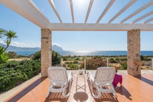 un patio con mesa, sillas y el océano en Casa Lia e Nino a San Vito Lo Capo, en San Vito lo Capo