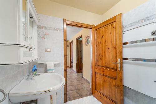 baño con lavabo blanco y puerta de madera en Casa Oleandro en Buggerru