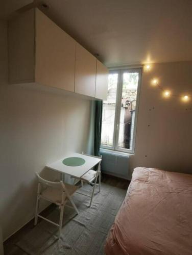 Schlafzimmer mit einem Bett, einem Tisch und einem Fenster in der Unterkunft Cozy Studio*Near Paris*Ideal Couple in Boulogne-Billancourt