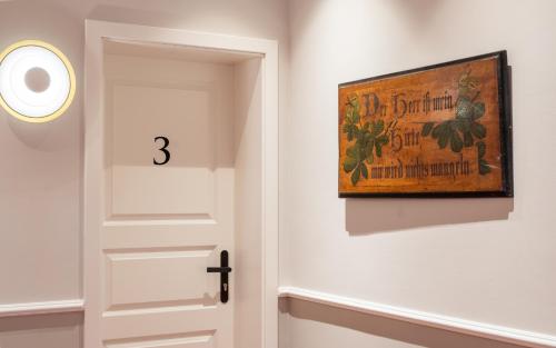 a door with a painting on the wall and a clock at Up Hus Hotel Neuruppin in Neuruppin