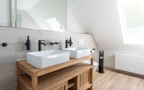 ein Badezimmer mit zwei Waschbecken auf einer Holztheke in der Unterkunft Up Hus Hotel Neuruppin in Neuruppin