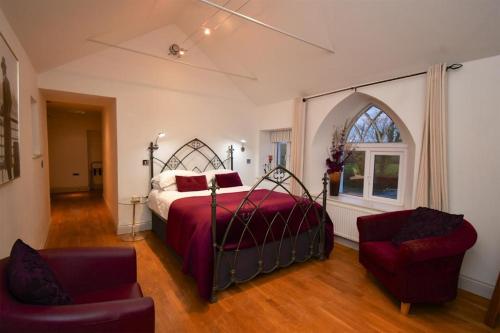 um quarto com uma cama, uma cadeira e uma janela em Tudor Lodge Bed & Breakfast em Manorbier