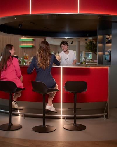 a woman sitting at a bar with a bartender at Novotel Zurich City West in Zürich