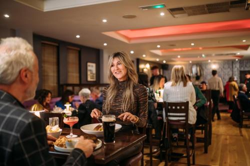 a woman sitting at a table in a restaurant at The Valley Hotel & Carriage Gardens in Fivemiletown