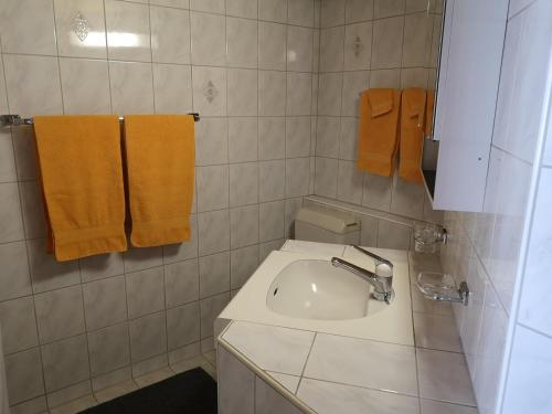 een badkamer met een wastafel en 2 oranje handdoeken bij Bolgenstrasse 12 in Bolgen