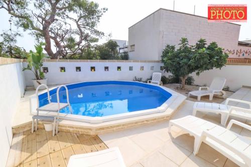 a pool on a patio with white furniture and chairs at Vistamare in Alliste