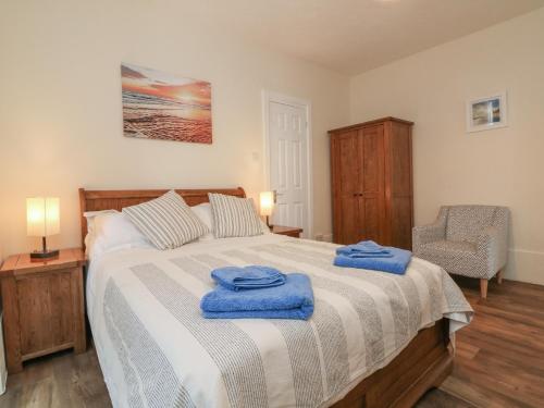 a bedroom with a large bed with blue towels on it at At the Bay Apartment in Ilfracombe