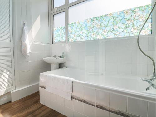 Un baño blanco con bañera y lavabo. en At the Bay Apartment, en Ilfracombe