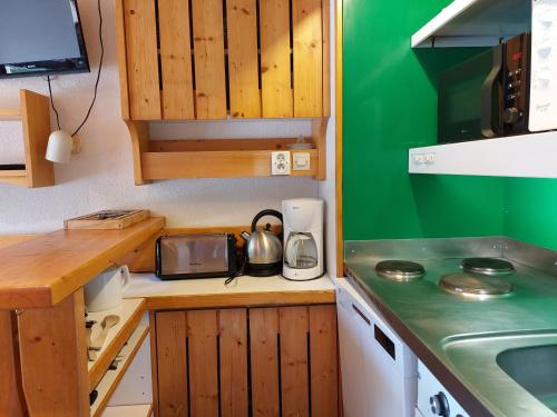Elle comprend une petite cuisine avec des placards en bois et un évier. dans l'établissement Duplex pour 6 à Arc 1800, proche des pistes, village charmant avec balcon exposition sud-ouest. - FR-1-411-734, à Bourg-Saint-Maurice