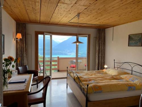 Schlafzimmer mit einem Bett und einem Tisch sowie einem Balkon in der Unterkunft Hotel Haltenegg in Heiligenschwendi