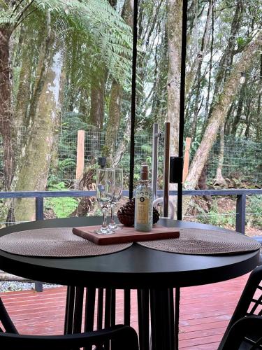 a table with a wine glass and a bottle on it at Alpes Canela chales em meio a natureza in Canela