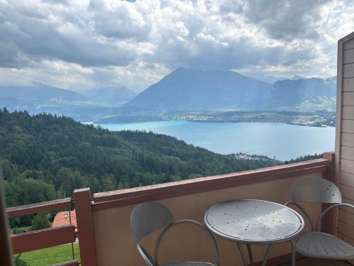 a table and chairs on a balcony with a view of a lake at Rooms Haltenegg in Heiligenschwendi