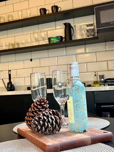a bottle of wine and two glasses on a table at Alpes Canela chales em meio a natureza in Canela