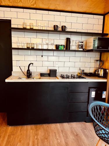 a kitchen with a black and white counter top at Alpes Canela chales em meio a natureza in Canela