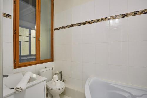 une salle de bain blanche avec des toilettes et un lavabo dans l'établissement Studio Tour Eiffel by Studio prestige, à Paris