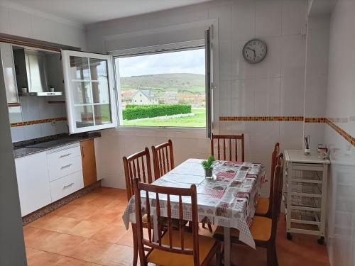 casa sisargas في لا كورونيا: مطبخ مع طاولة مع كراسي وساعة على الحائط