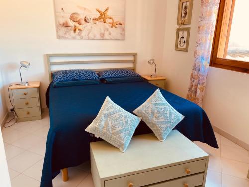 Sa Suergia Apartment في فيلاسيميوس: غرفة نوم بسرير وملاءات ووسائد زرقاء