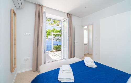 Beautiful Apartment In Dubrovnik With Jacuzzi في دوبروفنيك: غرفة بيضاء بسرير ازرق ونافذة