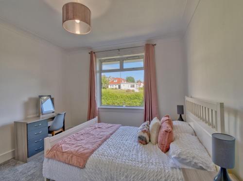sypialnia z dużym łóżkiem i oknem w obiekcie Seamill Cottage w mieście West Kilbride