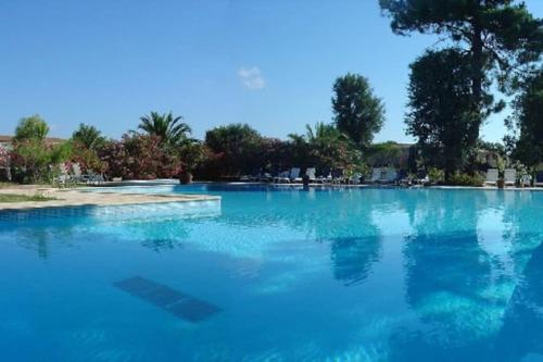 a large pool of blue water with trees in the background at Fiori Di Cala Rossa Appartement T3 dans résidence hôtellière chez Virginie in Lecci