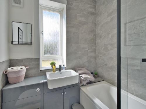 baño con lavabo, bañera y ventana en Seamill Cottage, en West Kilbride