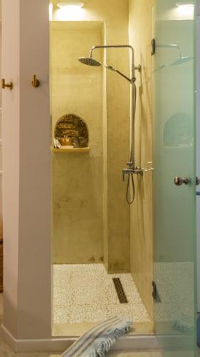 a shower with a glass door in a bathroom at Manus Dei Exclusive Suites in Pythagoreio