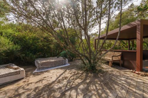 a patio with two beds and a tree at Villa Smeralda in Porto Rotondo