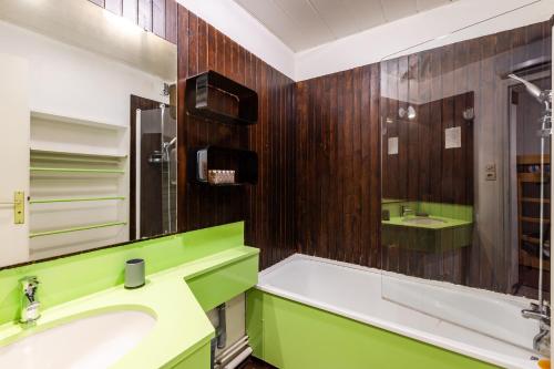 een groene badkamer met een bad en een wastafel bij Les Mélèzes - Appt à Serre Chevalier in Saint-Chaffrey