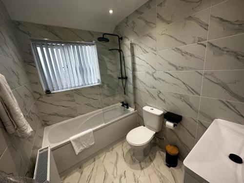 a bathroom with a toilet and a tub and a sink at Modern 3 Bedroom home near Birmingham Airport & NEC in Sheldon