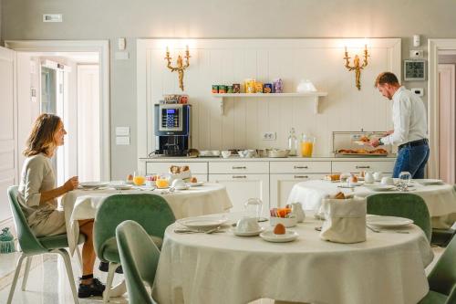 a man and a woman in a kitchen with tables at Villa Dafne Valpolicella B&B Adults only, no smoking, no pets in SantʼAmbrogio di Valpolicella