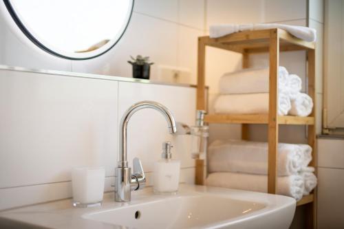 Maracoon - Suite Apartments Essen Messe I Great location في إيسن: حوض حمام مع مرآة ومجموعة من المناشف