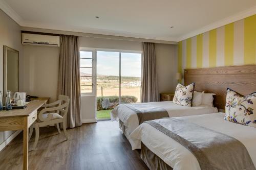 a hotel room with two beds and a desk and a window at Protea Hotel by Marriott Stellenbosch & Conference Centre in Stellenbosch