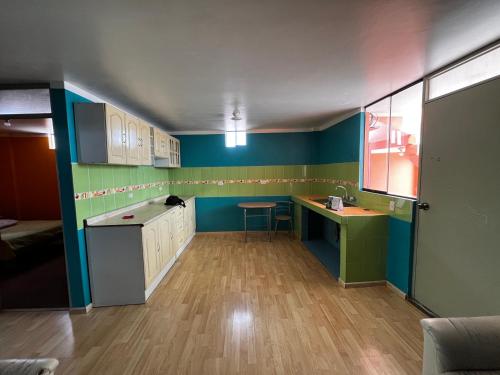 a kitchen with blue and green walls and wooden floors at UMERSA SUITE HOTEL in Espinar