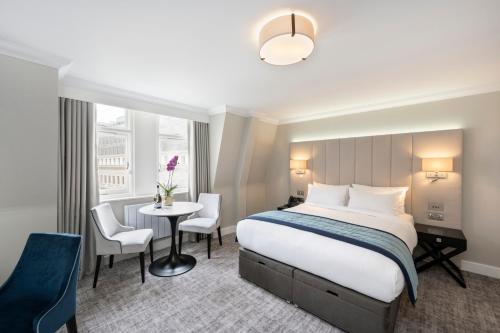 Una habitación de hotel con una cama, una mesa y sillas. en Tower Residences by Blue Orchid, en Londres