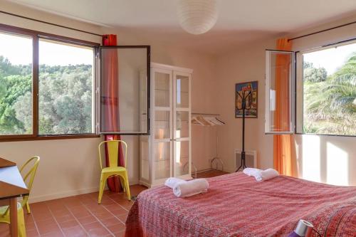 une chambre avec un lit et une table et deux fenêtres dans l'établissement SUPERBE VILLA CONTEMPORAINE: PISCINE ET VUE MER, à Ollioules