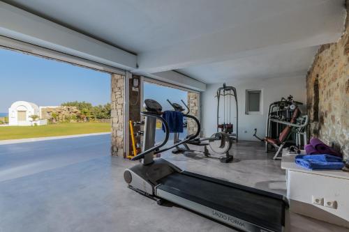 a gym with a treadmill and a large window at Spectacular Kalafatis Villa 1 Bedroom Villa Vibhu Private Jacuzzis & Infinity Pool in Kalafatis