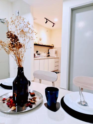 a white table with a vase and a plate of food at Bali Residence Melaka Condo in Malacca