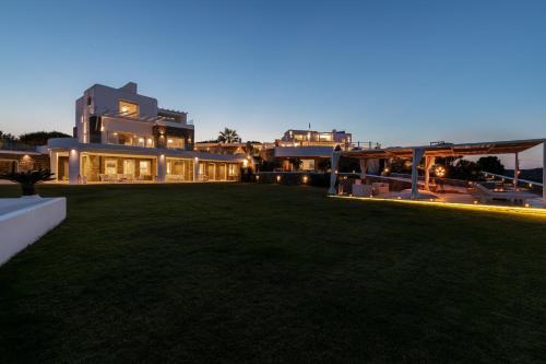 a large house with a lawn at night at Spectacular Kalafatis Villa 1 Bedroom Villa Vibhu Private Jacuzzis & Infinity Pool in Kalafatis