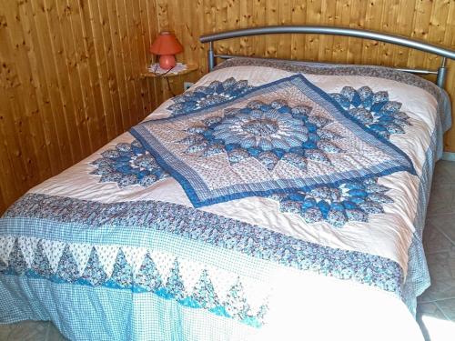 Una cama con un edredón azul y blanco. en Bungalow am Waldrand, en Barth