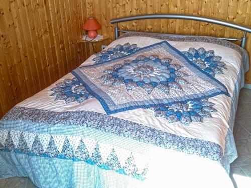 a bed with a blue and white quilt on it at Bungalow am Waldrand in Barth