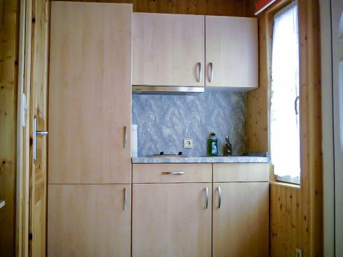cocina con armarios de madera, fregadero y ventana en Bungalow am Waldrand, en Barth