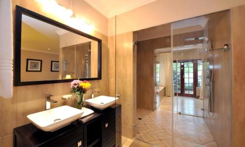 a bathroom with two sinks and a shower and a mirror at Lythwood Lodge in Lidgetton